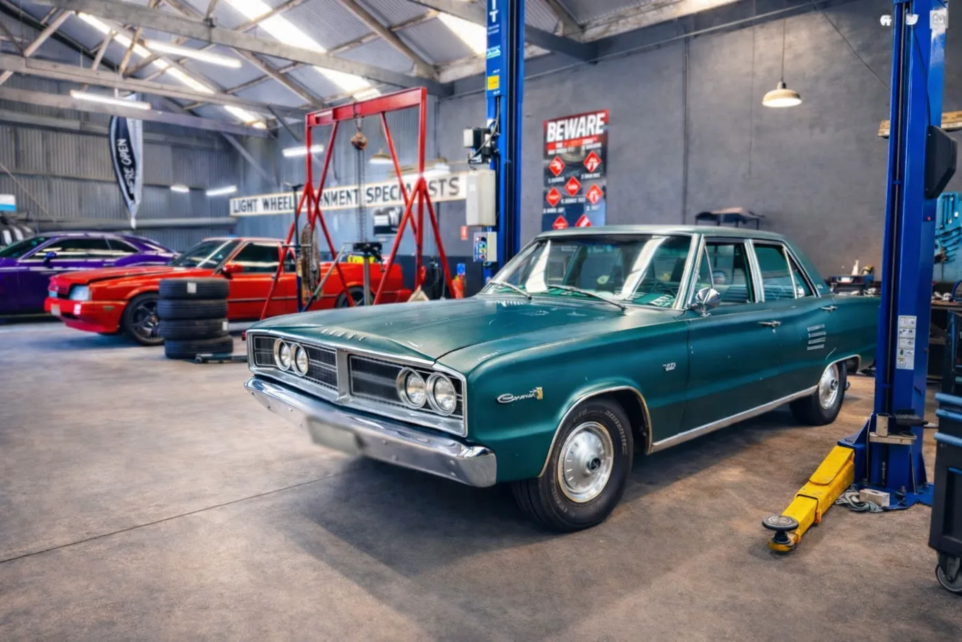 A teal classic sedan parked between the hoists on the workshop floor at 60 Byron Place
