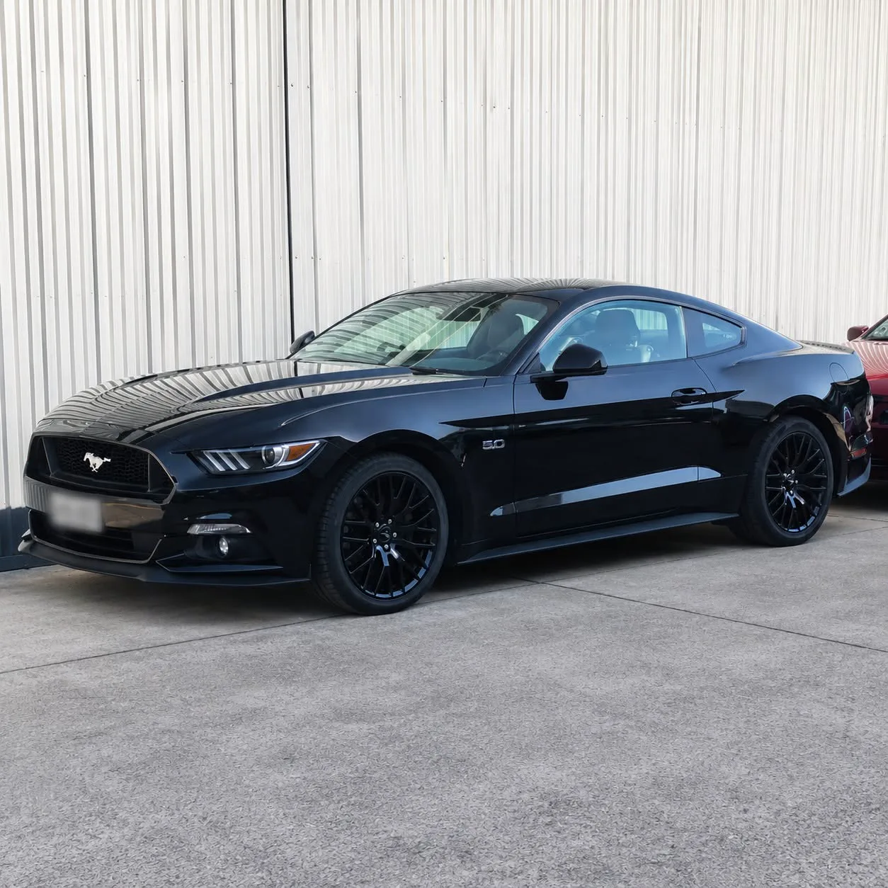 A black Ford Mustang inside the workshop