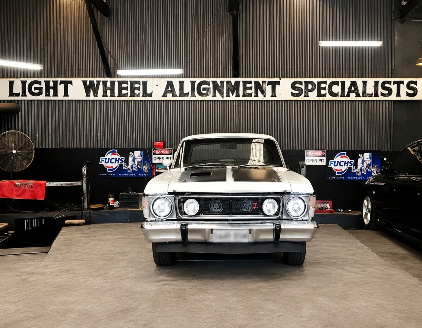 A Holden Monaro parked beneath the Light Wheel Alignment Specialists workshop sign