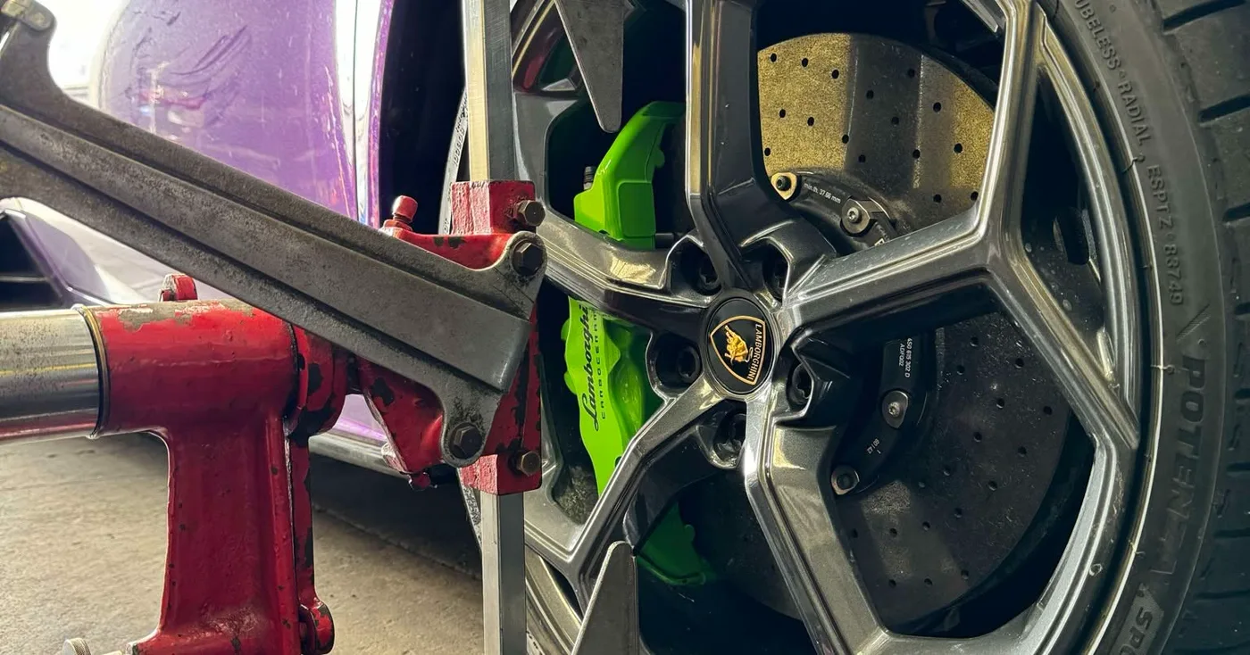 Alignment equipment set up against the front wheel of a car in the workshop