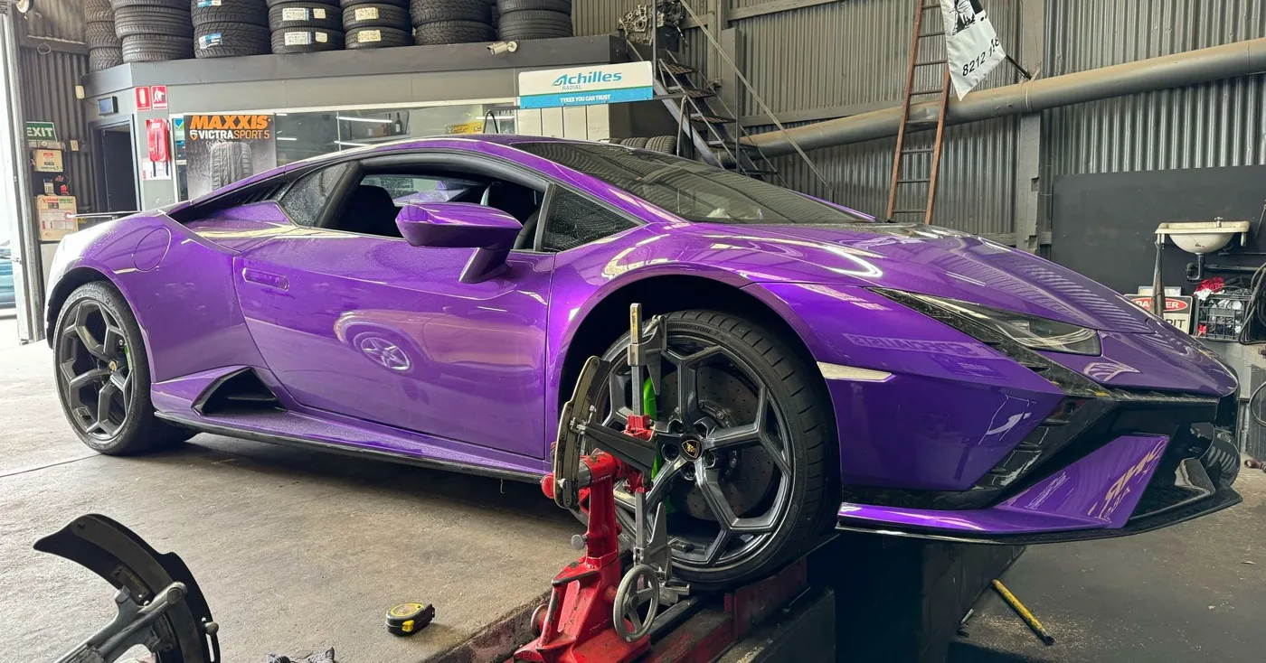 A purple Lamborghini Huracan with its front bumper removed for suspension work
