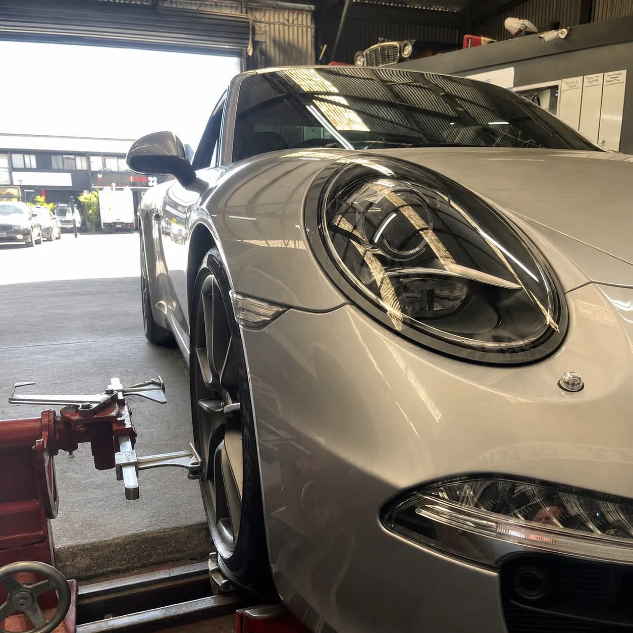 A silver Porsche 911 at the workshop roller door