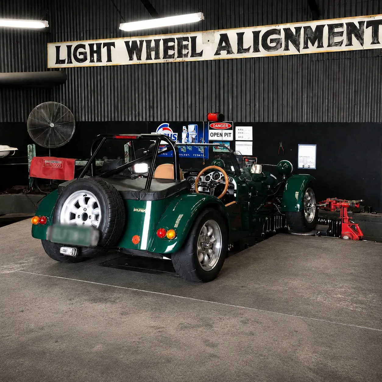 A green vintage racing car with a roundel on its bonnet, inside the workshop