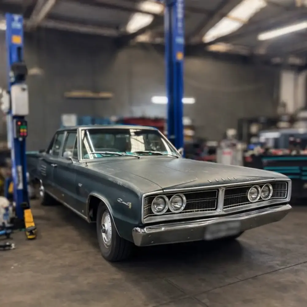 A classic car raised on the two post hoist inside the workshop